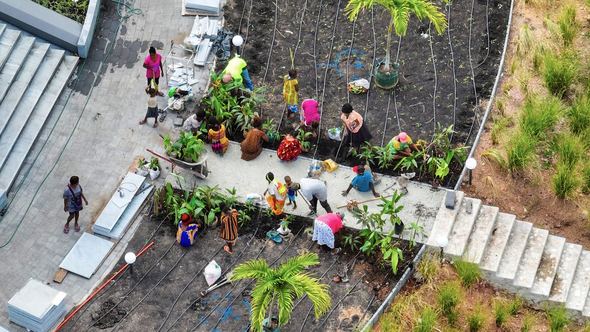 Vue aérienne de bénévoles préparant les jardins autour de la maison d’adoration.